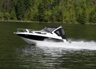 Bateau de plaisance blanc et noir naviguant sur un lac bordé de forêt