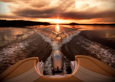 Sillage d'un bateau propulsé par un moteur hors-bord, sur un lac au coucher du soleil