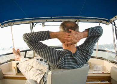 Plaisancier détendu, les mains derrière la tête, à bord de son bateau